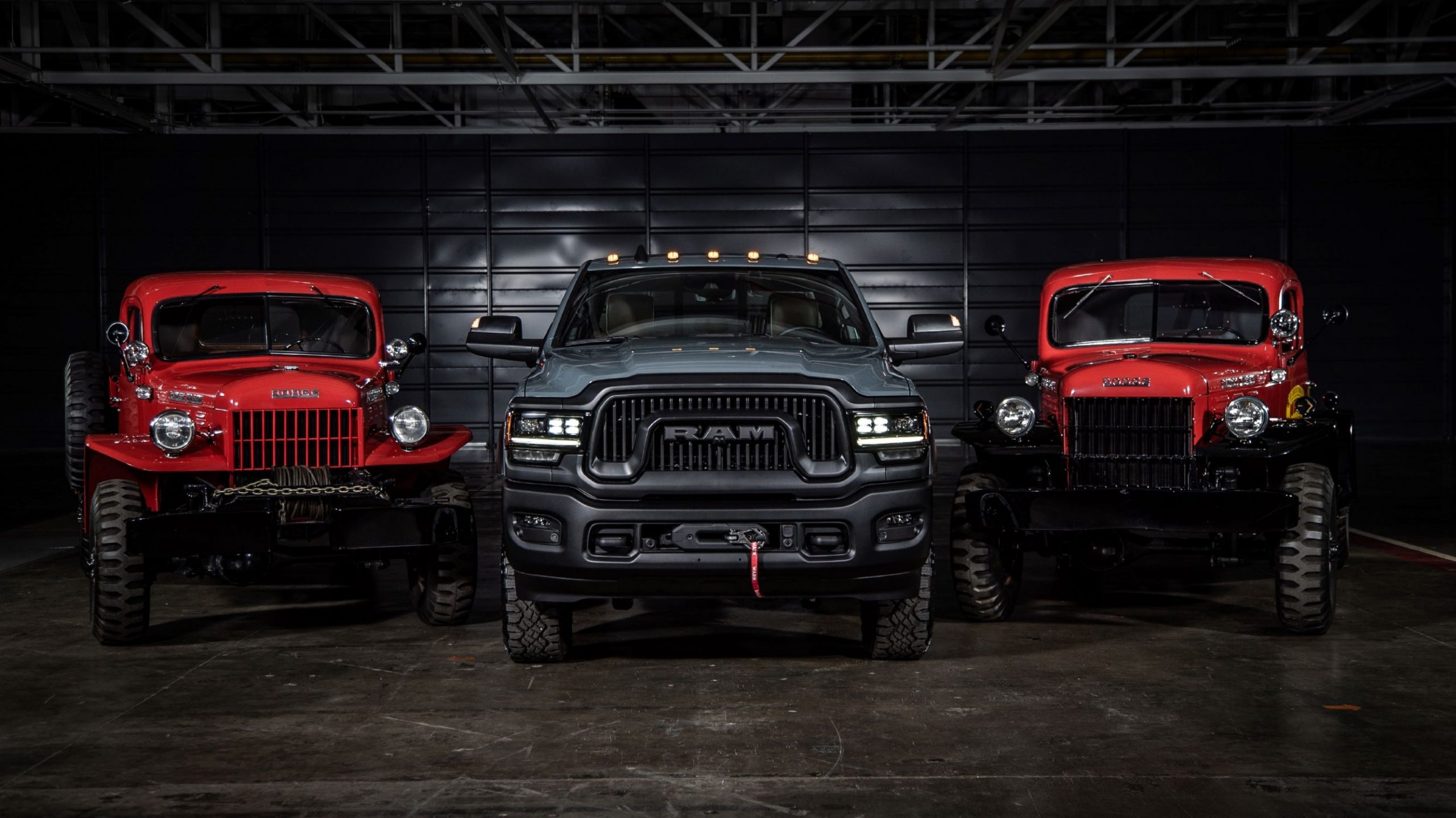 A gray 2021 Ram Power Wagon 75th Anniversary Edition flanked by a red 1946 Dodge Power Wagon and red Power Wagon Wrecker