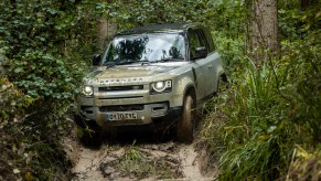 A 2021 Silver Land Rover Defender drives on rough terrain.