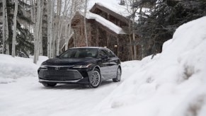 A black 2021 Toyota Avalon driving in the snow