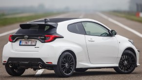 The rear 3/4 view of a white 2021 Toyota GR Yaris on a racetrack