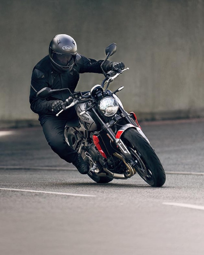 A black-clad rider riding a black-and-red 2021 Triumph Trident 660