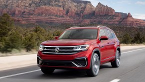 A red 2021 Volkswagen Atlas SEL Premium 4Motion on a paved road with mountains in the background.