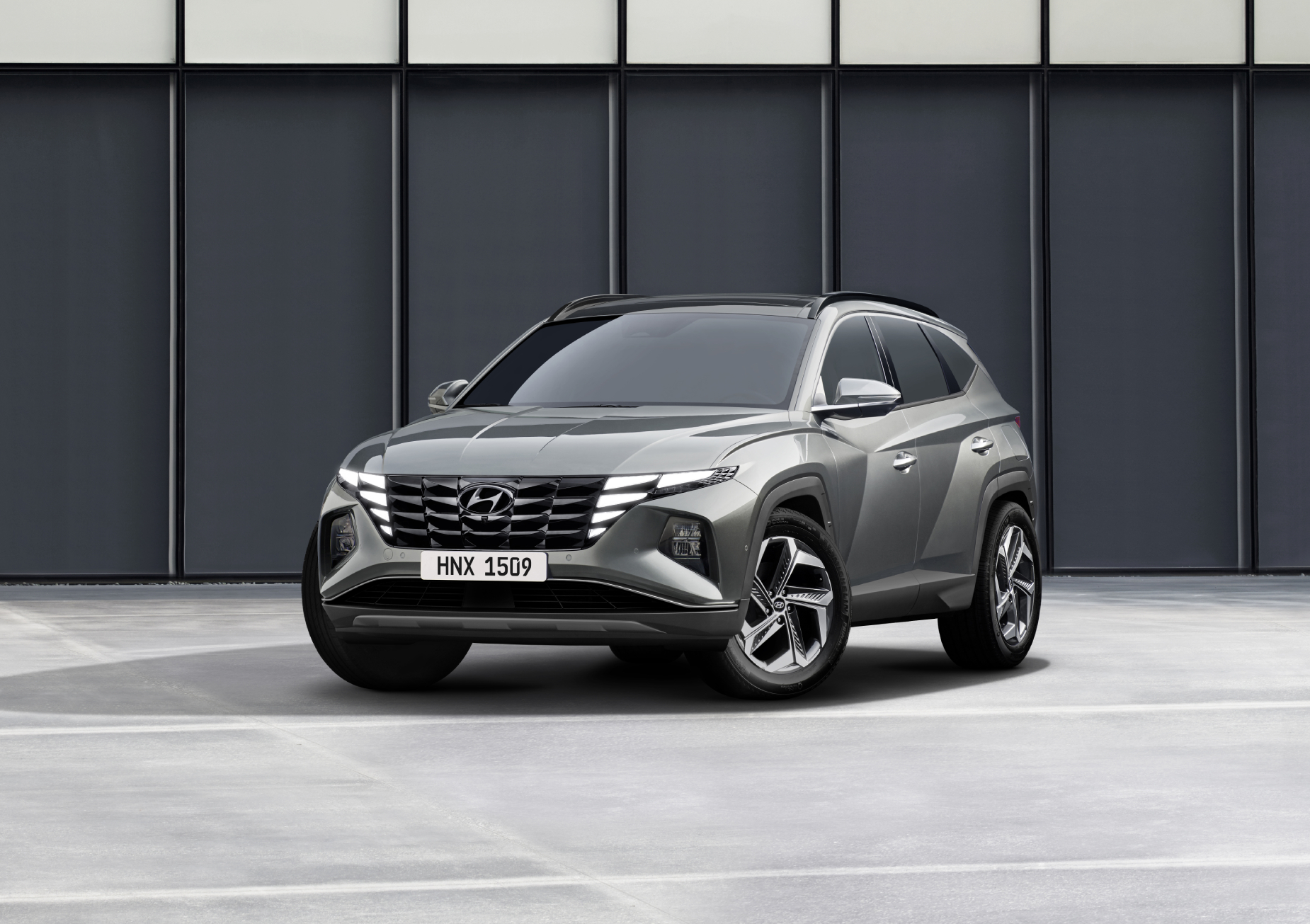 A grey 2022 Hyundai Tucson parked in front of a wall on display