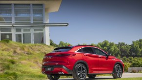 A red 2022 Infiniti QX55 driving away from a building