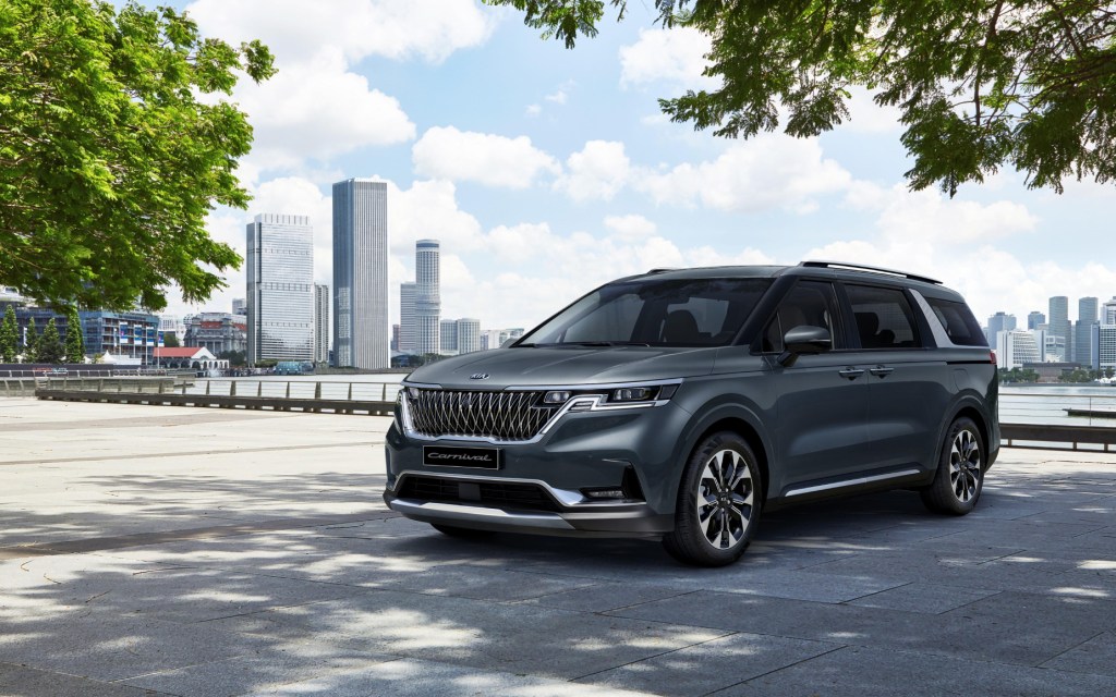 The 2022 Kia Sedona, aka 2022 Kia Carnival, parked on display with a cityscape in the background