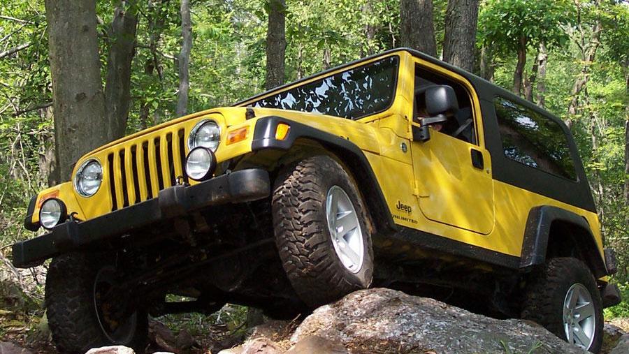 a yellow 2006 wrangler going off-road in the forest