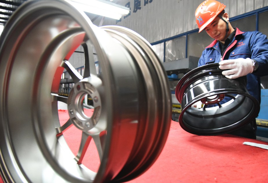 A worker inspects aluminum alloy wheel hubs at an aluminum company