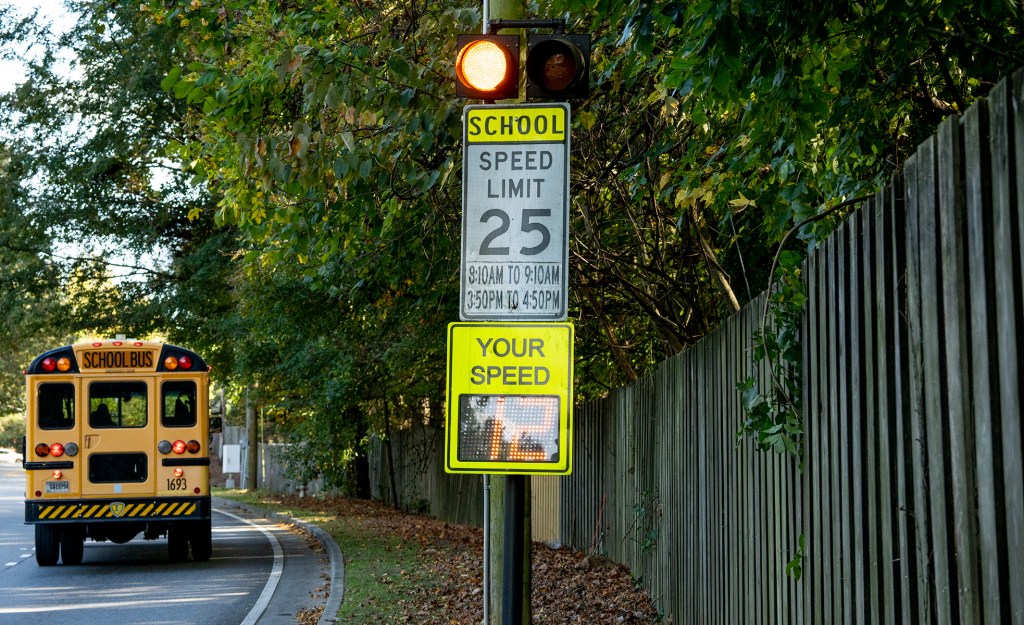 A school bus driving past a school zone safety beacon