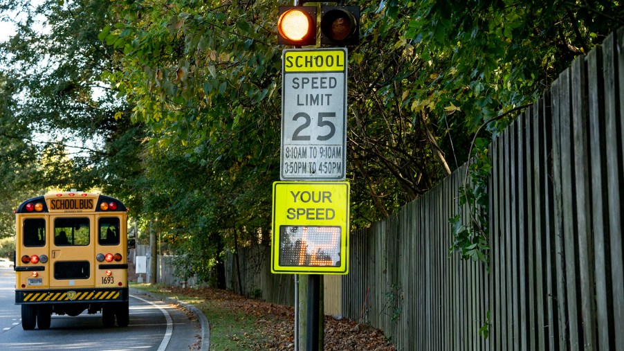 A school bus driving past a school zone safety beacon