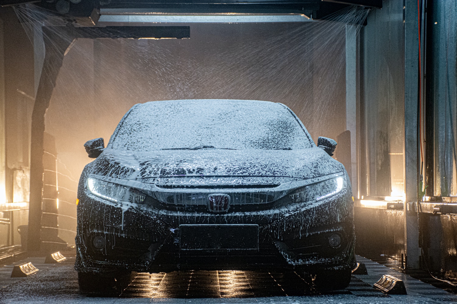 A full-service brushless car wash cleaning the exterior of an older Honda Accord.