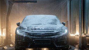A full-service brushless car wash cleaning the exterior of an older Honda Accord.