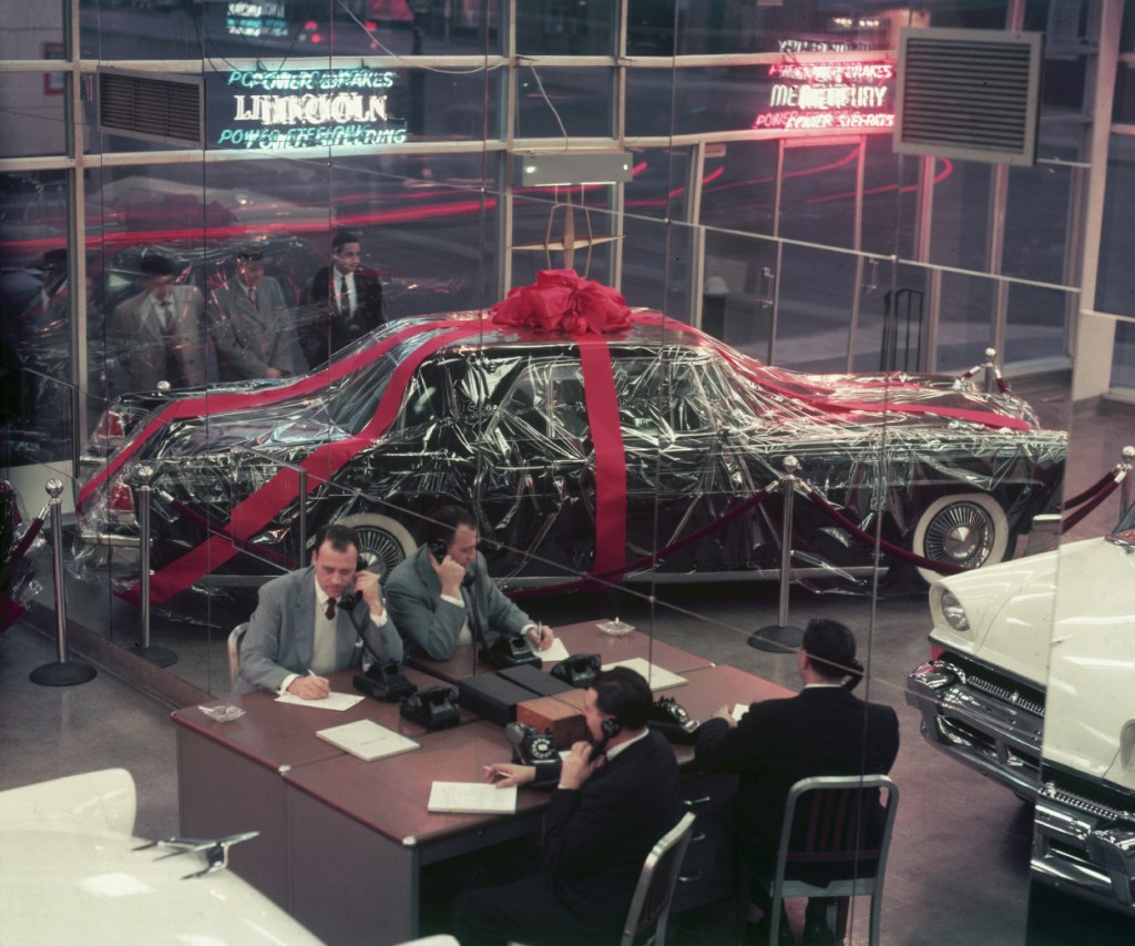 A car with a giant bow and gift wrap on display at a dealership