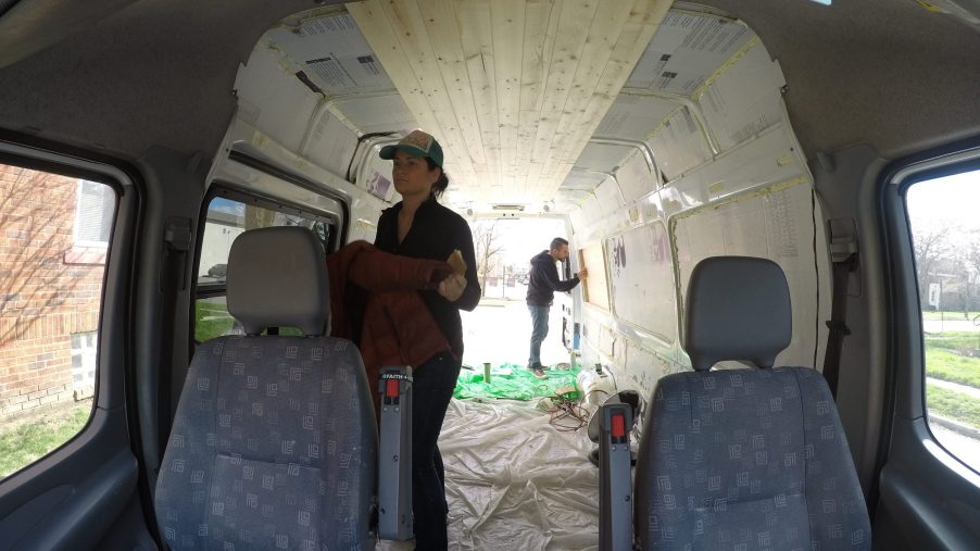 Two people work on converting a van into a camper