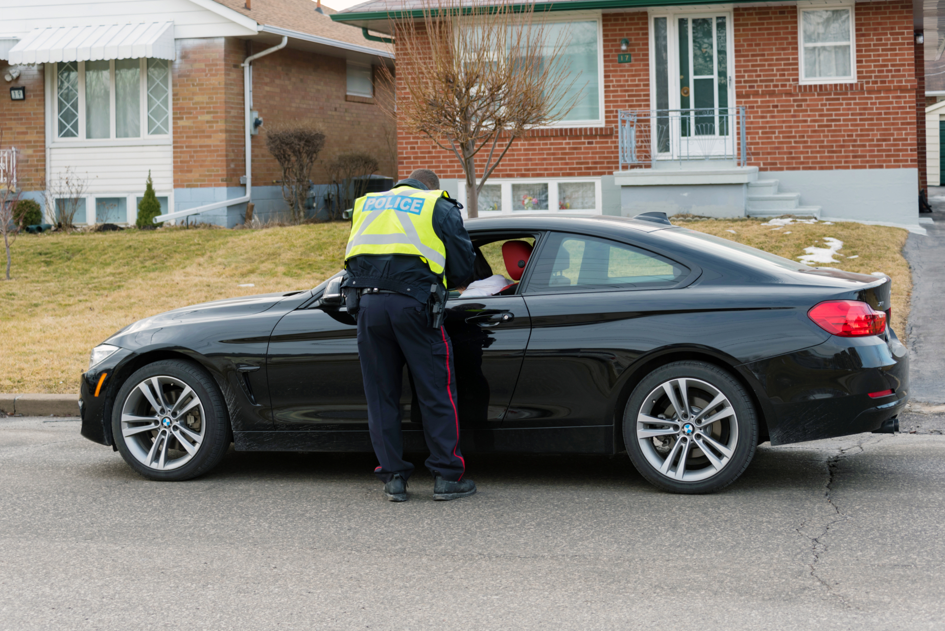 A cop giving a speeding ticket to a driver in a black sedan