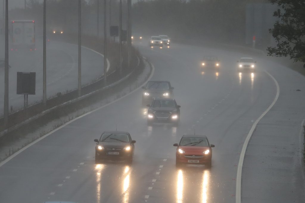 Cars driving on a highway in the rain, correctly not using their hazard lights