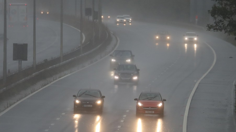 Cars driving on a highway in the rain, correctly not using their hazard lights