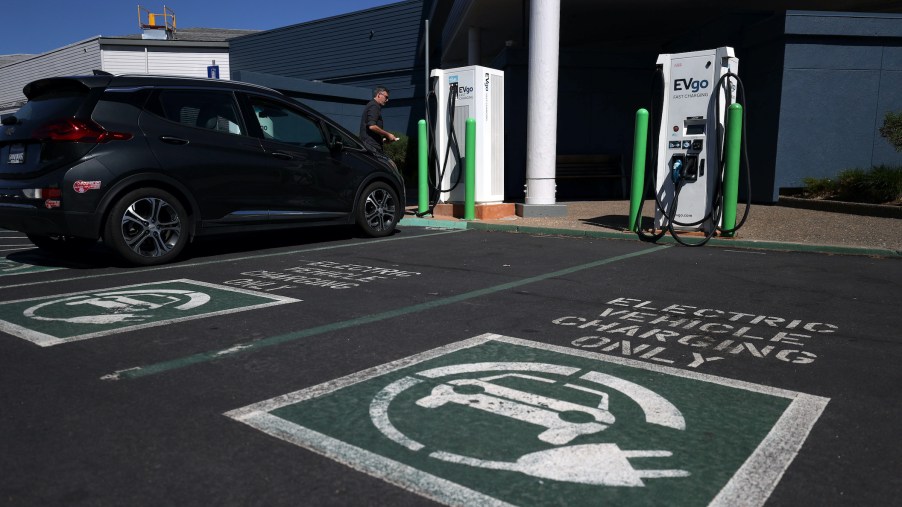 An electric car owner prepares to charge his car at an electric car charging station EV charging