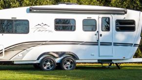 A white 2021 Terra Oasis travel trailer RV is parked on grass.