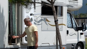 A man pets his dog inside a motorhome RV in a public parking in Castellon