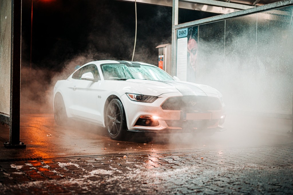A white Ford Mustang going through a no touch car wash