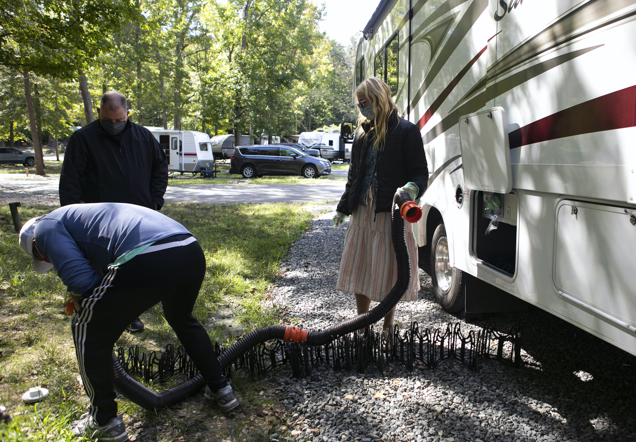 RV instructor Freddie Heller, left, teaches Washington Post travel writer Andrea Sachs and Christian Arriola how to hook up water and sewage lines to their rented RV