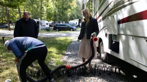 RV instructor Freddie Heller, left, teaches Washington Post travel writer Andrea Sachs and Christian Arriola how to hook up water and sewage lines to their rented RV