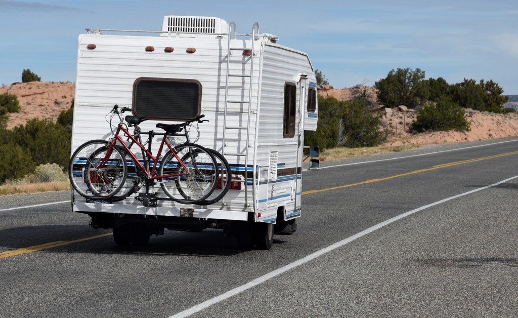 A tourist in an RV with bicycle racks approaches the small town of Chimayo, New Mexico