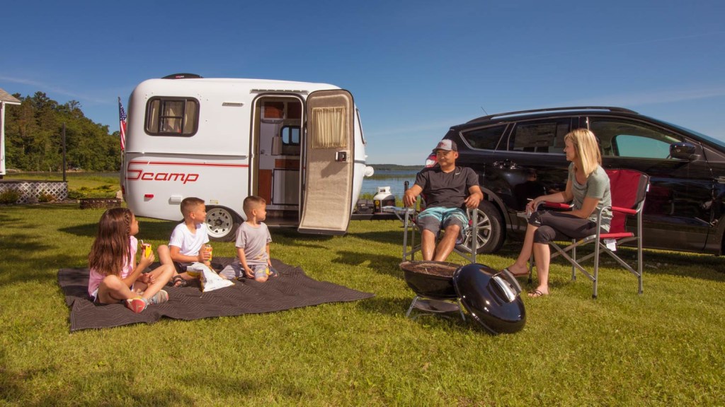 A family sitting outside in front of a Samp 13' Trailer.