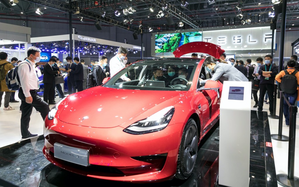 People view a Tesla Model 3 electric car at the auto exhibition area of the third International Import Expo