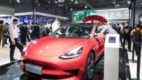 People view a Tesla Model 3 electric car at the auto exhibition area of the third International Import Expo