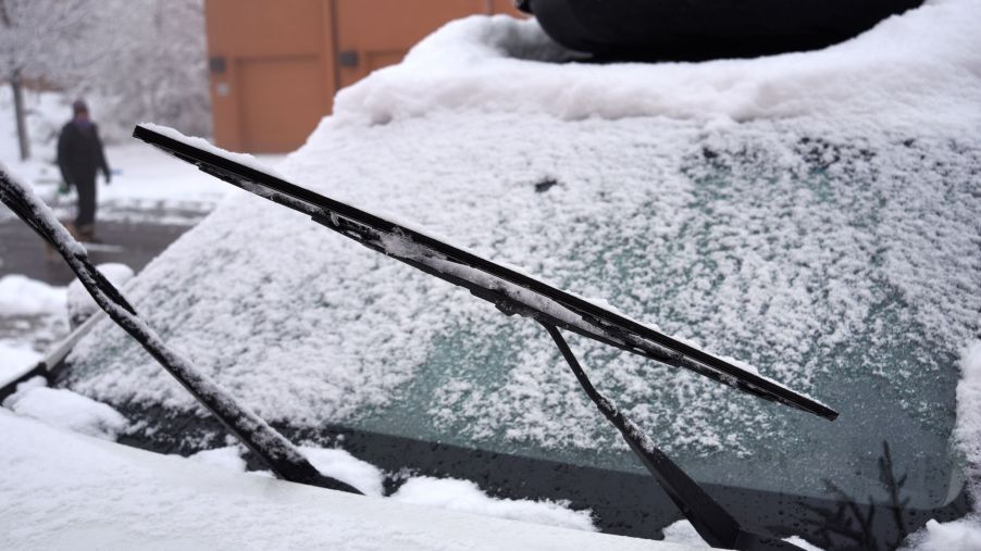 The windshield wipers and wiper blades of a snow-covered car
