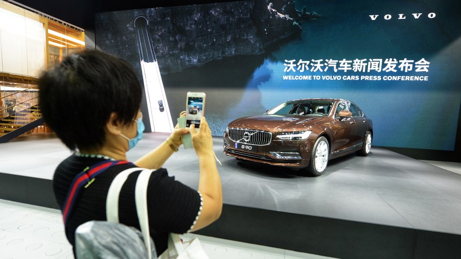 A woman takes photos of a Volvo S90 sedan during Chengdu Motor Show 2020 at Western China International Expo City