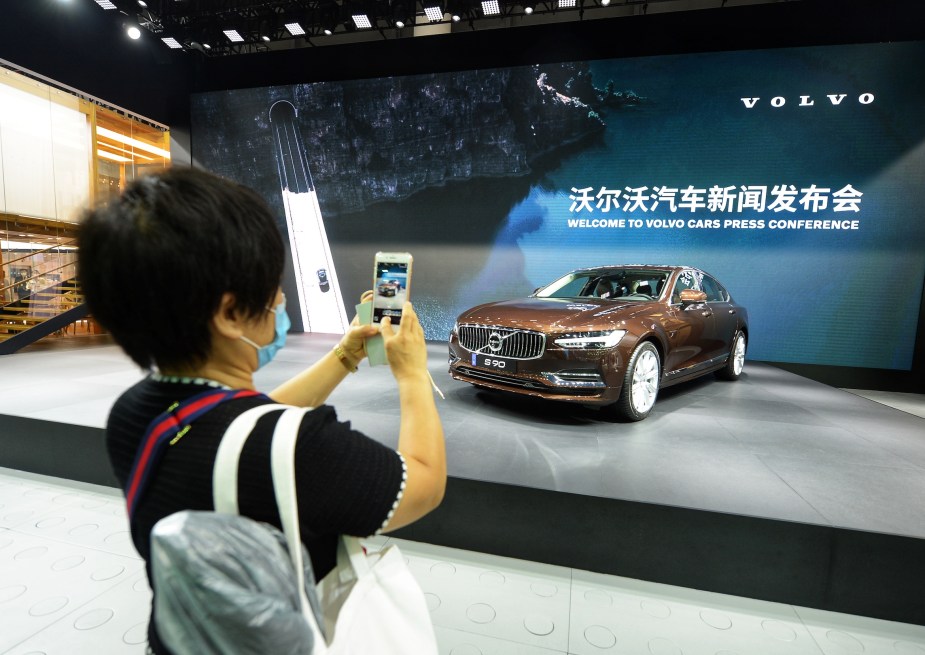 A woman takes photos of a Volvo S90 sedan during Chengdu Motor Show 2020 at Western China International Expo City