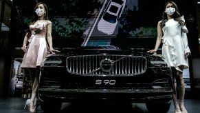 Models wear masks as a precaution while displaying a Volvo S90 in the Volvo stand during the 18th Central China International Auto Show