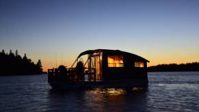 A Daigno Koroc P houseboat floats on the water at sunset.