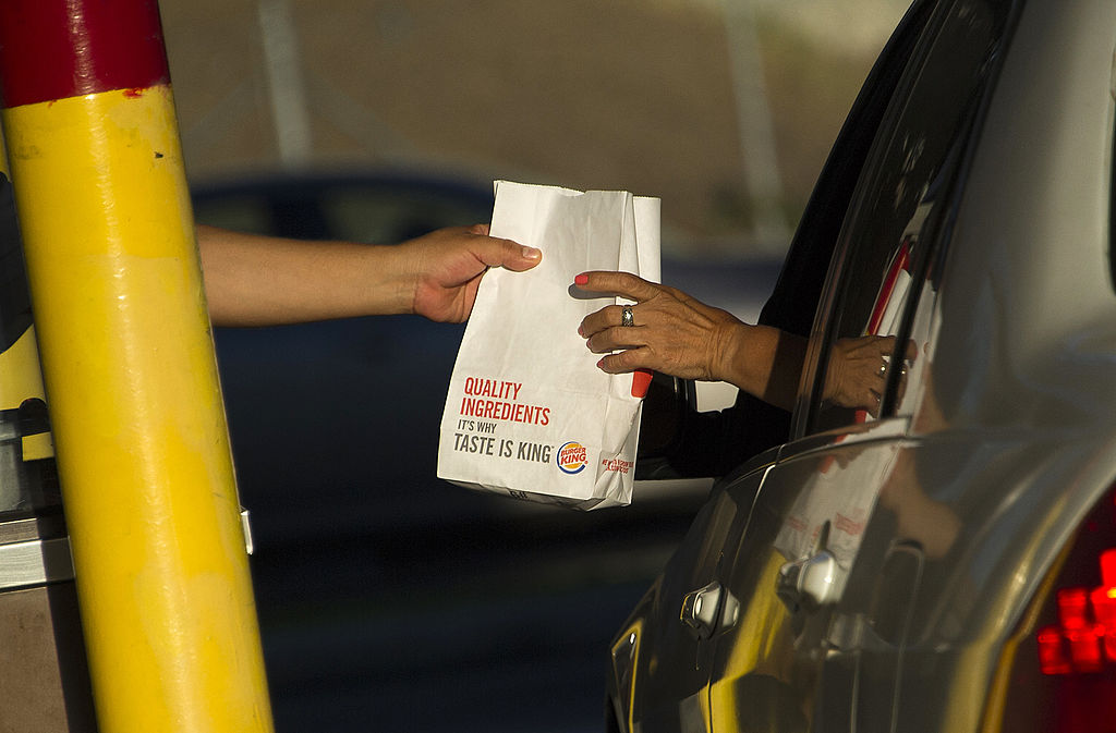 A worker hands food to a customer in a car at a Burger King restaurant.