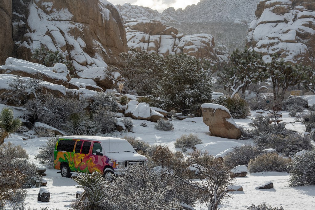 Snow blankets Joshua Tree National Park and RV camper van
