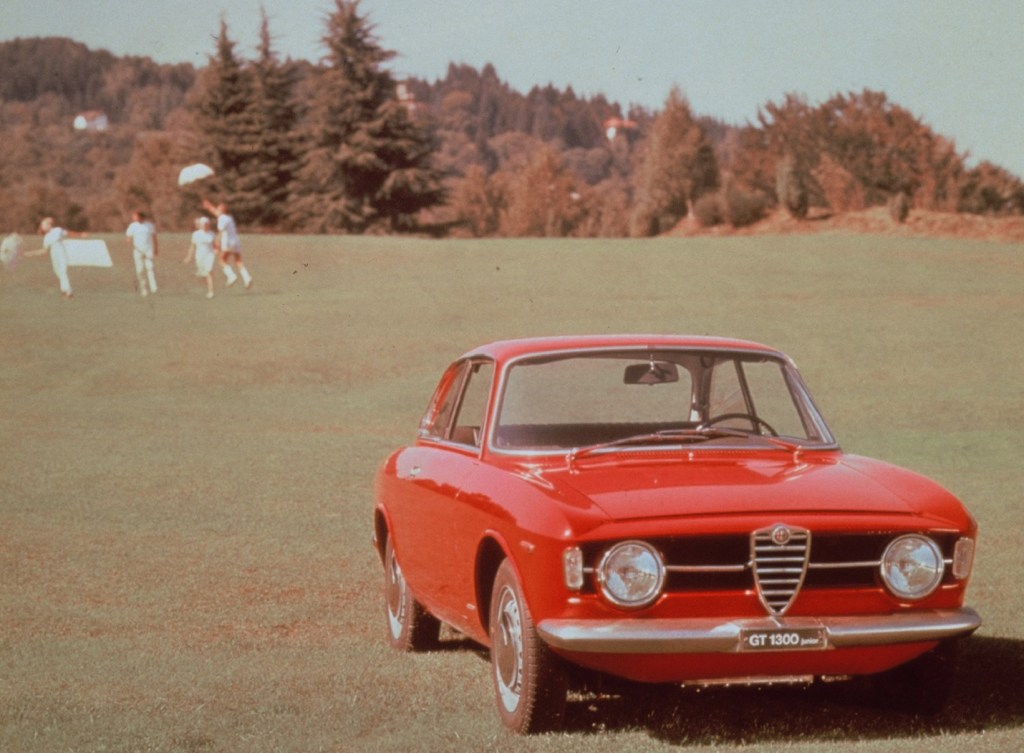 A red 1967 Alfa Romeo GT 1300 Junior in a field