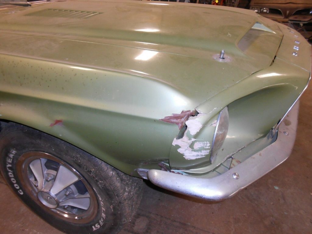 The damaged front facia and fender of a lime green 1968 Shelby GT350 that is at auction. 