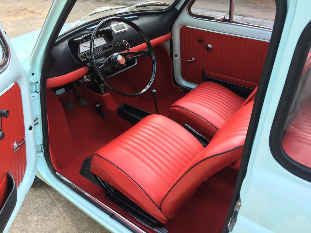 The 1972 Fiat Nuova 500L's red vinyl seats and padded black dashboard