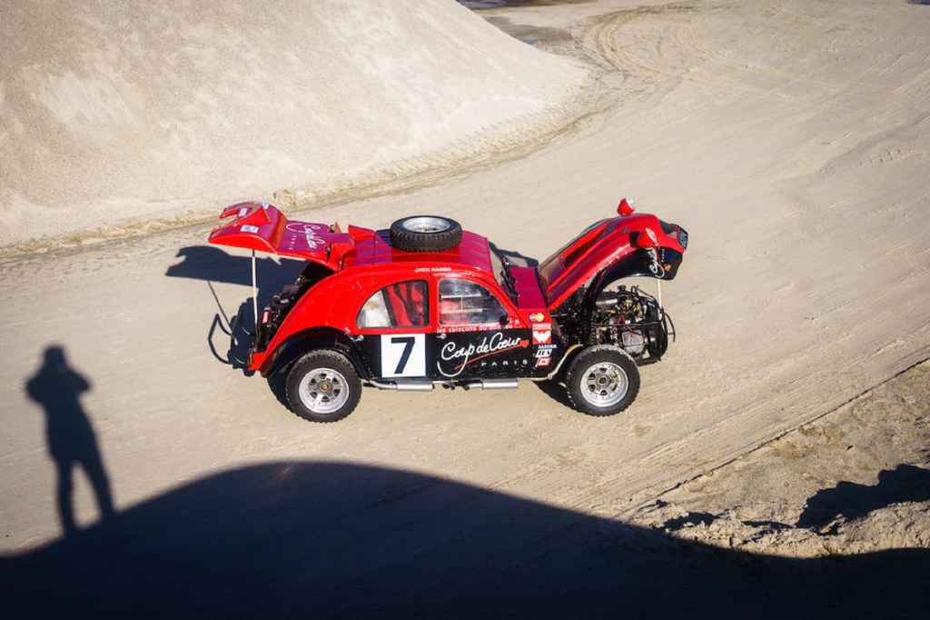 An overhead side view of the black-and-red 1974 twin-engine Citroen 2CV 4x4 rally car in a quarry