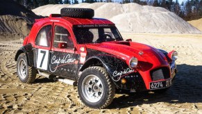 A red-and-black 1974 twin-engine Citroen 2CV 4x4 rally car in a quarry