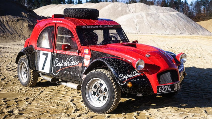A red-and-black 1974 twin-engine Citroen 2CV 4x4 rally car in a quarry