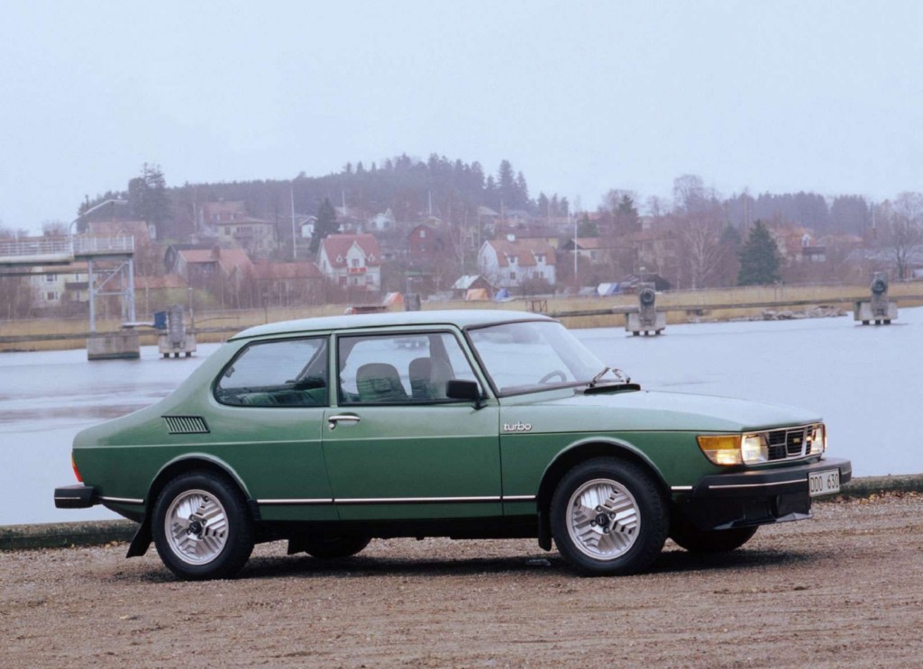 The side view of a green 1978 Saab 99 Turbo by a harbor
