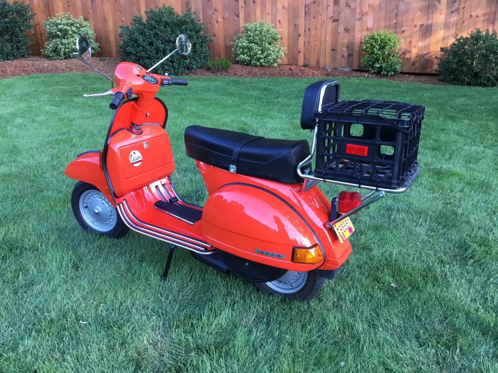 The rear 3/4 view of a red 1980 Vespa P125X