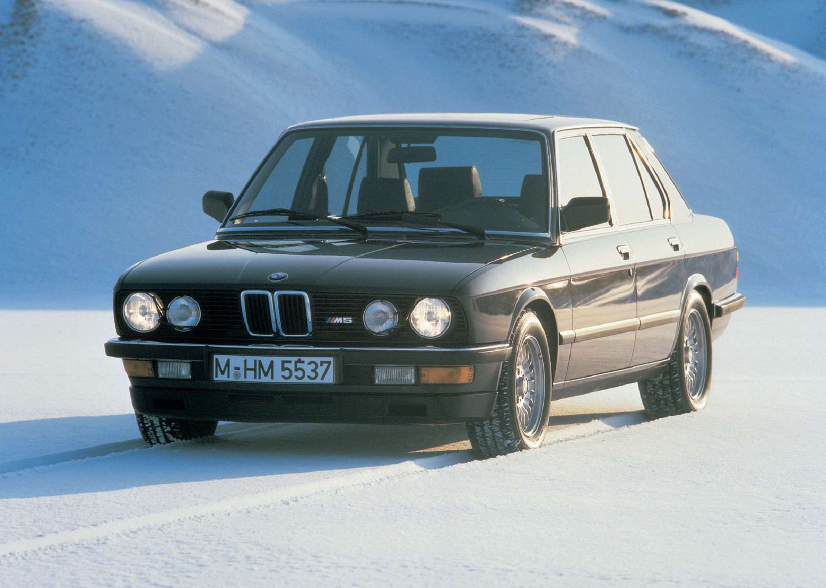 A black 1985 E28 BMW M5 on a snowy mountain