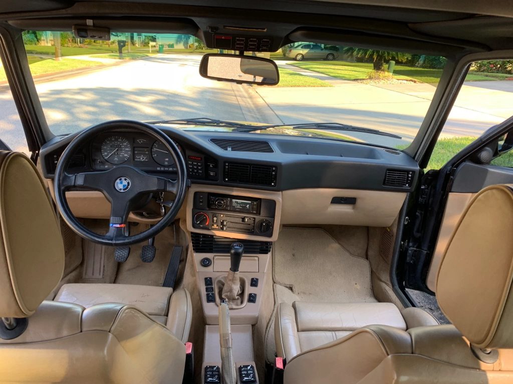 The tan-leather front seats and black-and-tan dashboard of a 1988 E28 BMW M5