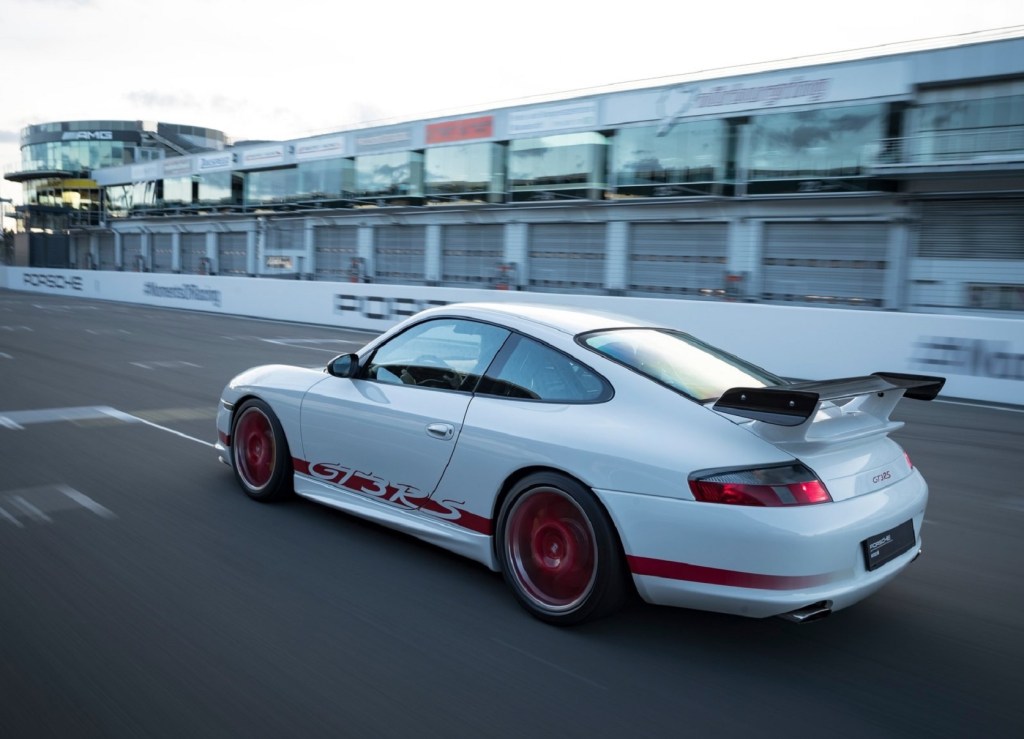 The rear 3/4 view of a white-and-red 2004 Porsche 911 GT3 RS on a track