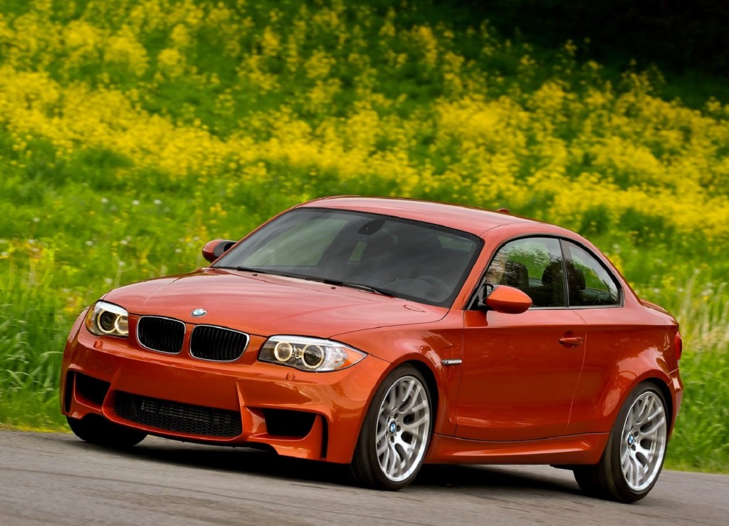 An orange 2011 BMW 1 Series M Coupe by a grassy field