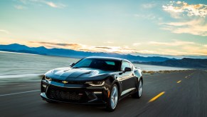 A dark-colored 2016 Chevrolet Camaro drives on a paved road outside Salt Lake City, Utah.